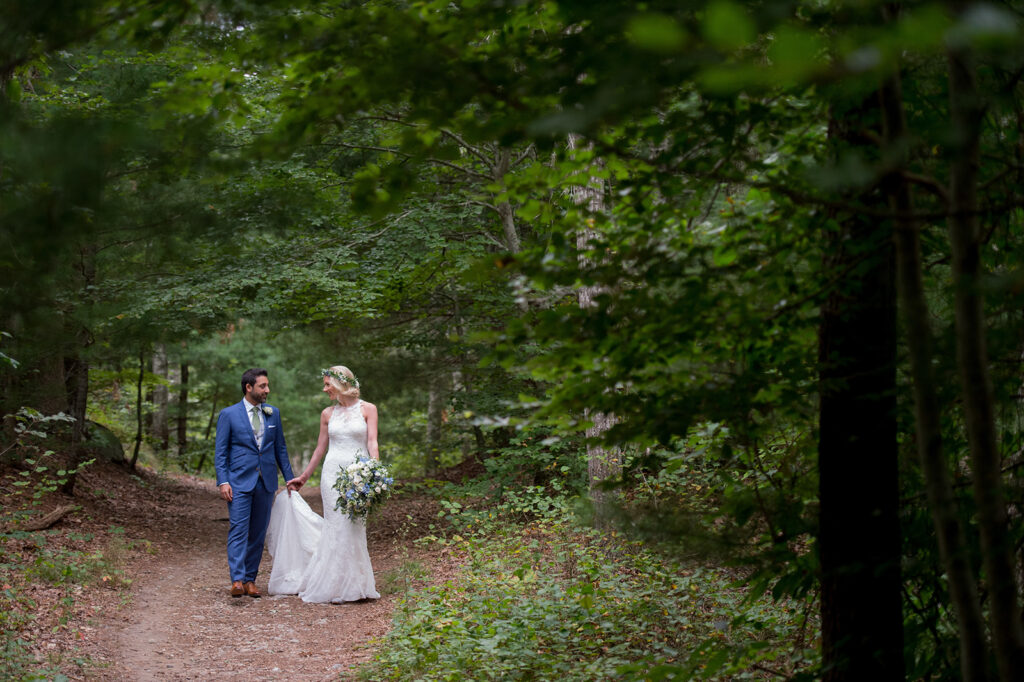 bride and groom walking together on path in woods