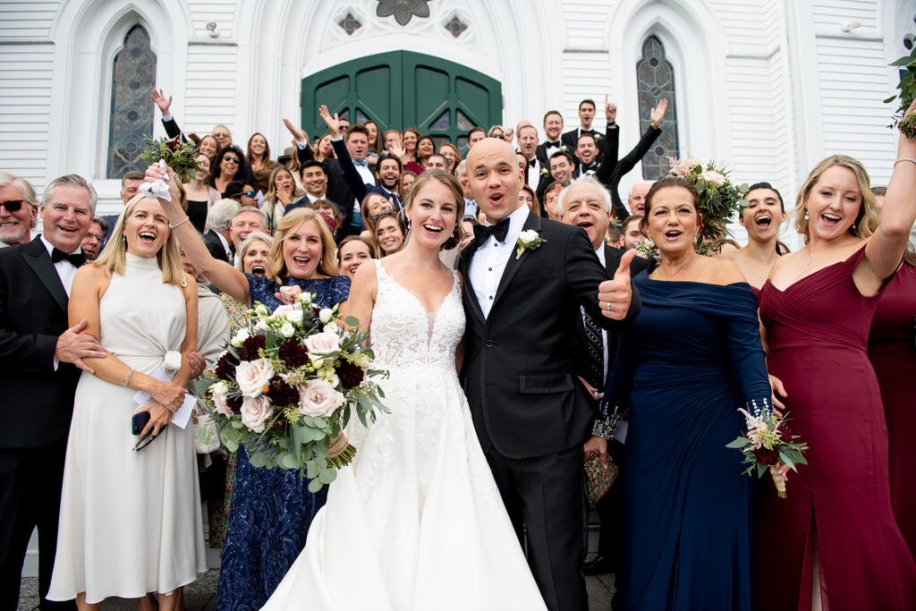 wedding photo of the full family in front of the church with the bride and groom