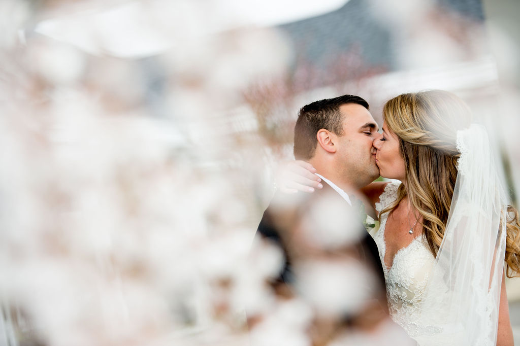 Bride and Groom kissing with spring flowers around them 