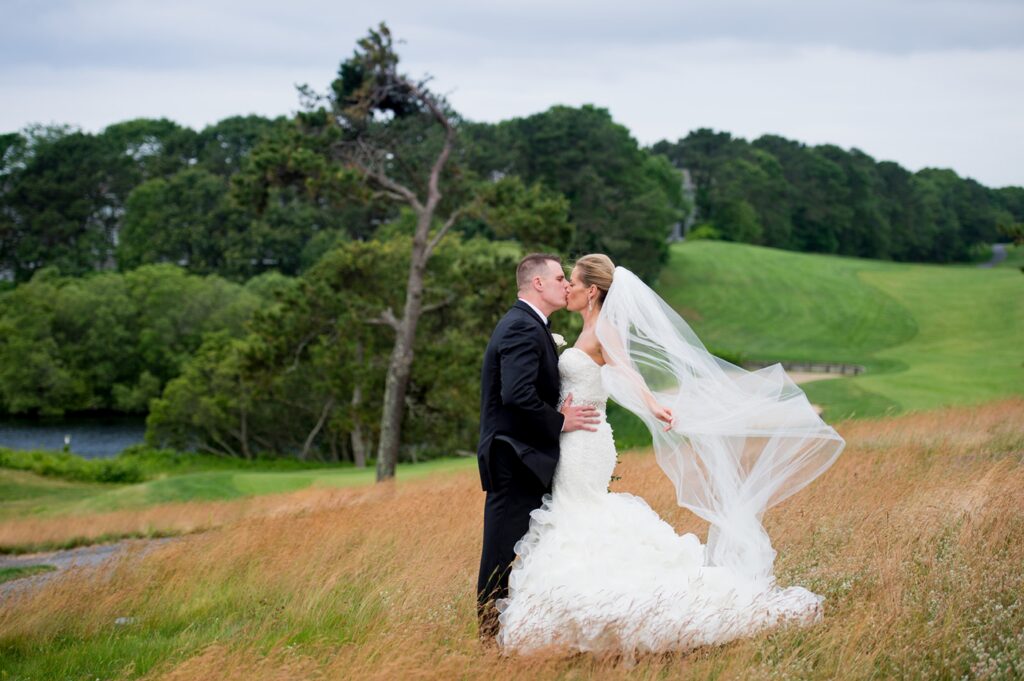 Bride and Groom kissing as brides veil flys in the wind