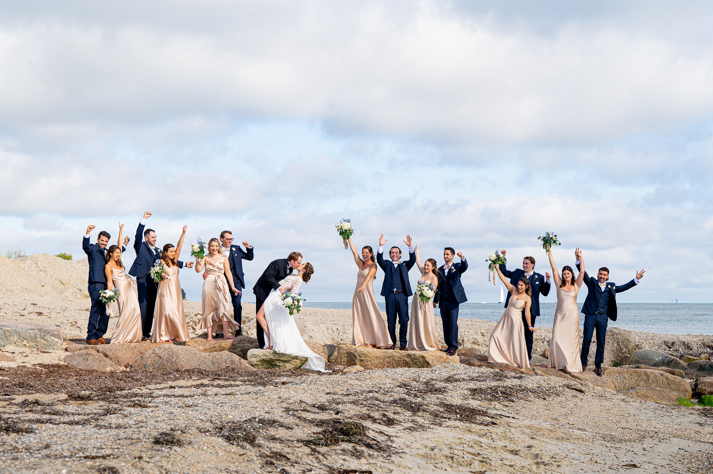Cape Cod wedding party on beach cheering well the bride and groom kiss.