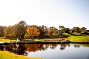 Fall wedding photo of bride and groom with reflection in pond at willowbend  