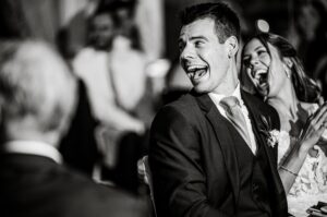 Couple laughing at wedding speeches black and white photo