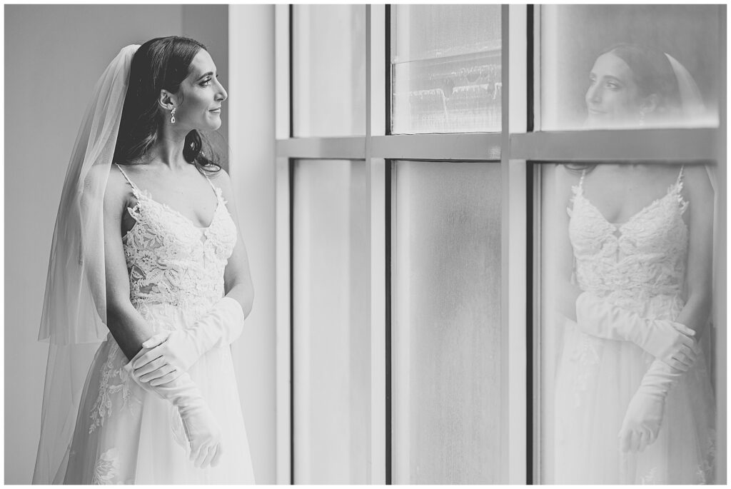 bridal portrait of bride looking out a window with her reflection 