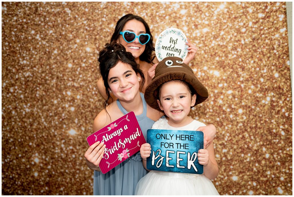 guests smile and hold up signs in the photo booth during the wedding reception