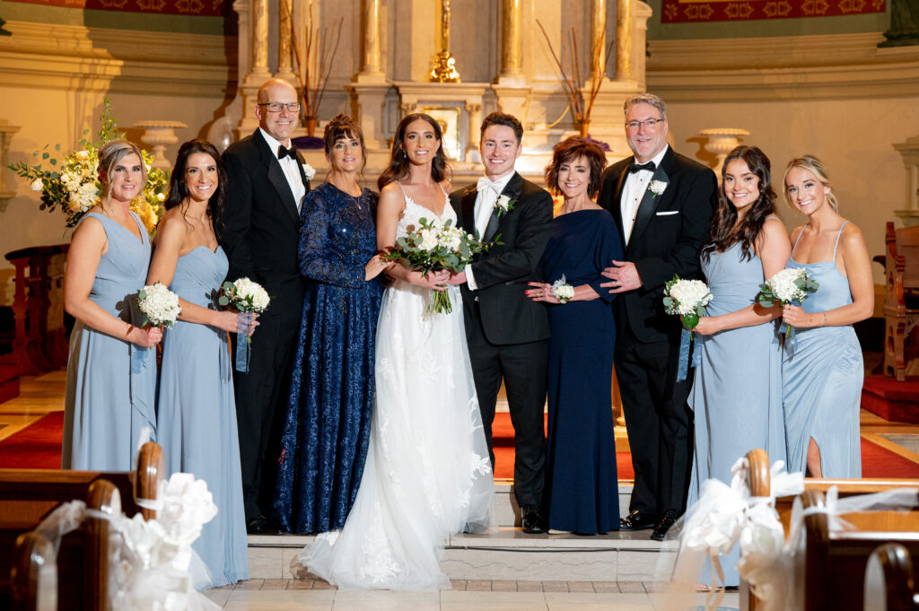 bride and groom pose with parents and siblings after church ceremony