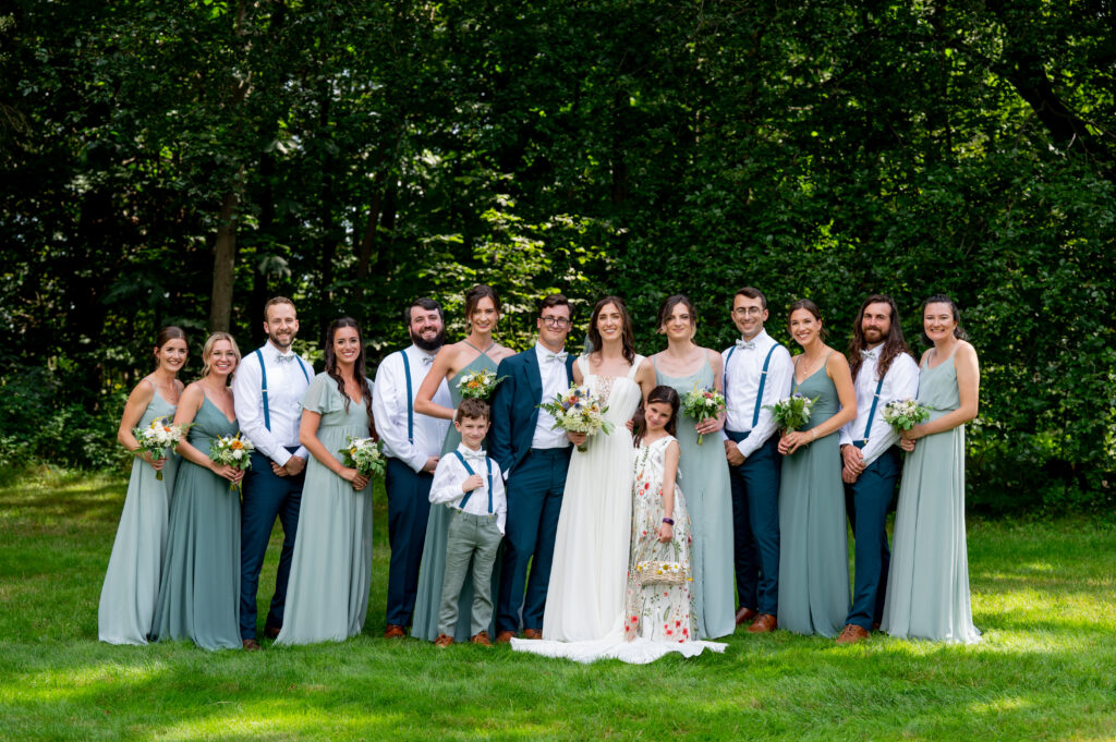 bride and groom post with wedding party with bridesmaids wearing teal dresses 