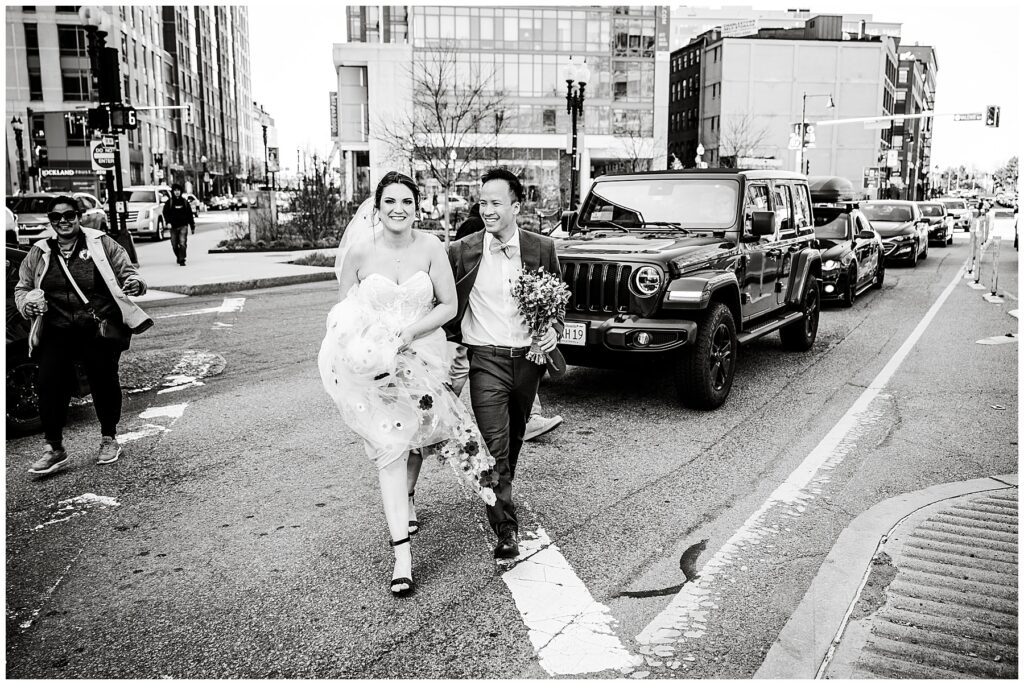 black and white photo of bride and groom crossing the street