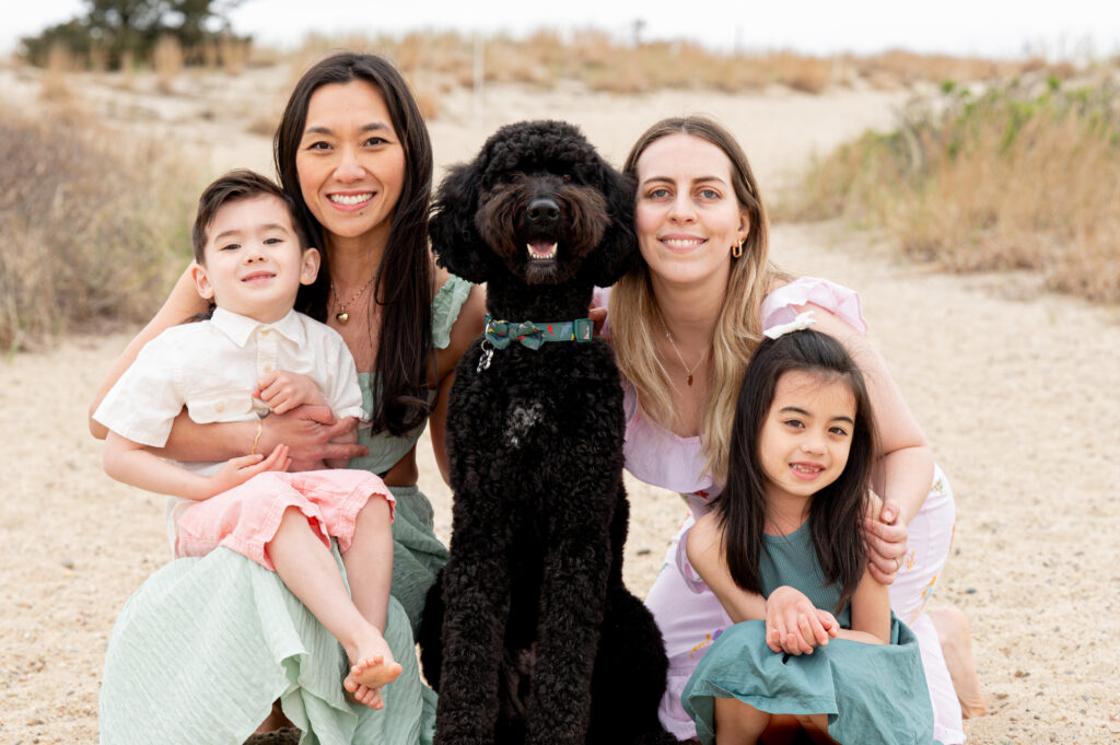 a family of four smiles at the camera with their brown dog in the middle