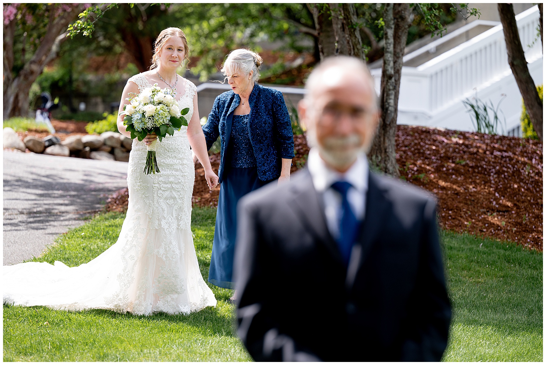 the bride and her mother stand behind the bride's father before the first look