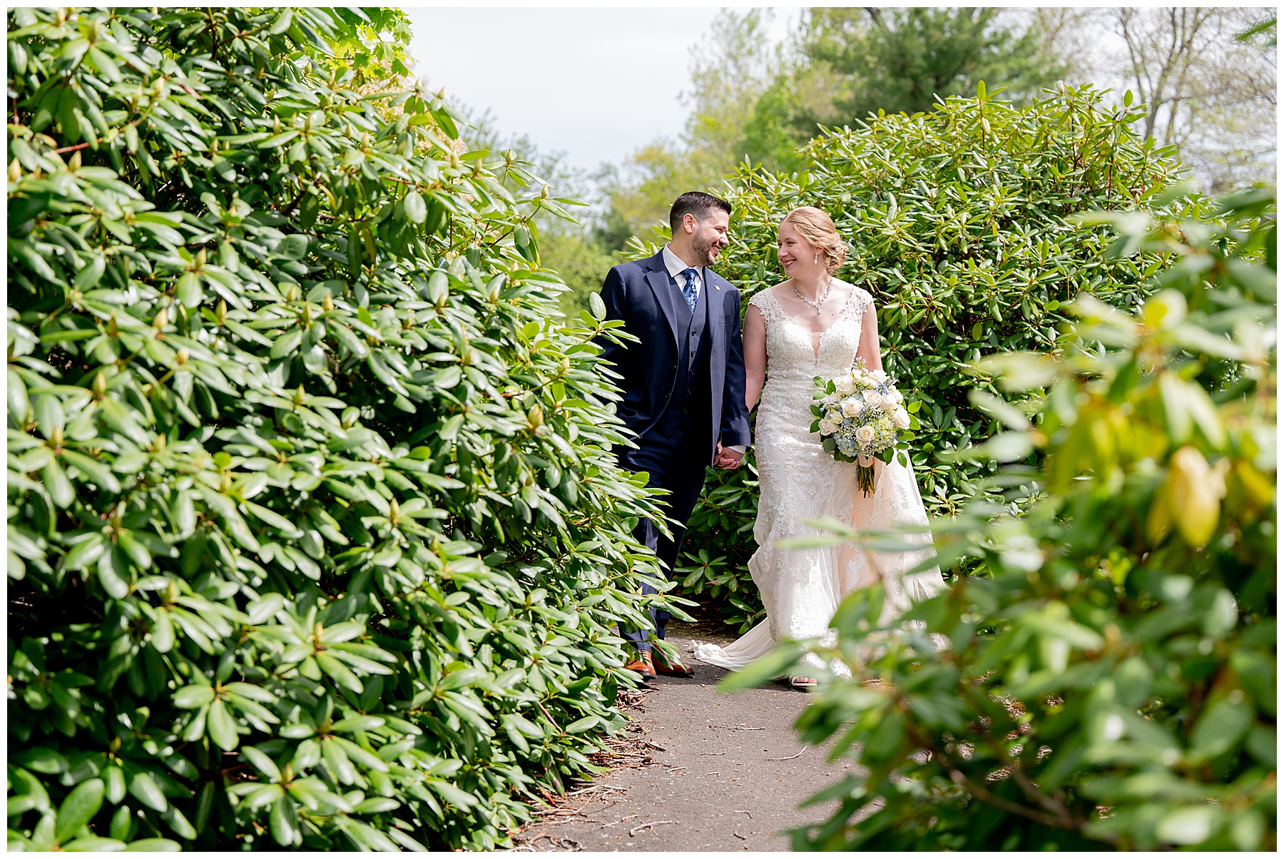 the bride and groom walk through a path filled with greenery 