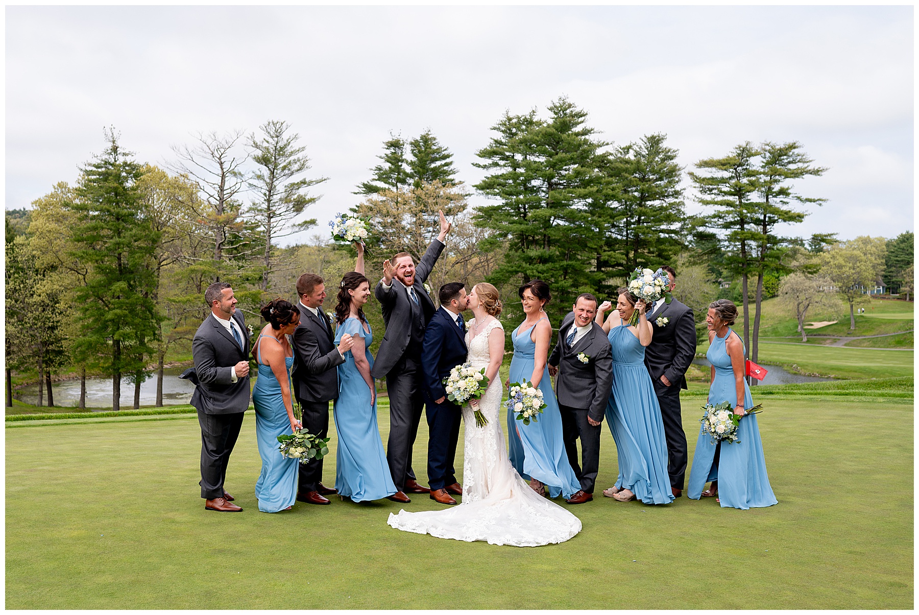 the wedding party stands around the bride and groom smiling and celebrating