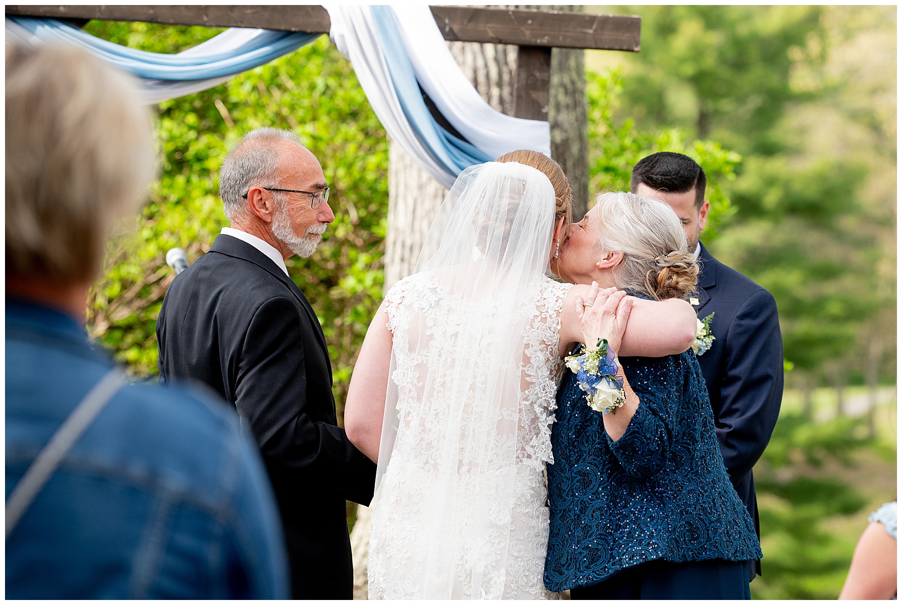 mother of the bride kisses her daughter's cheeck at the end of the aisle before the wedding ceremony