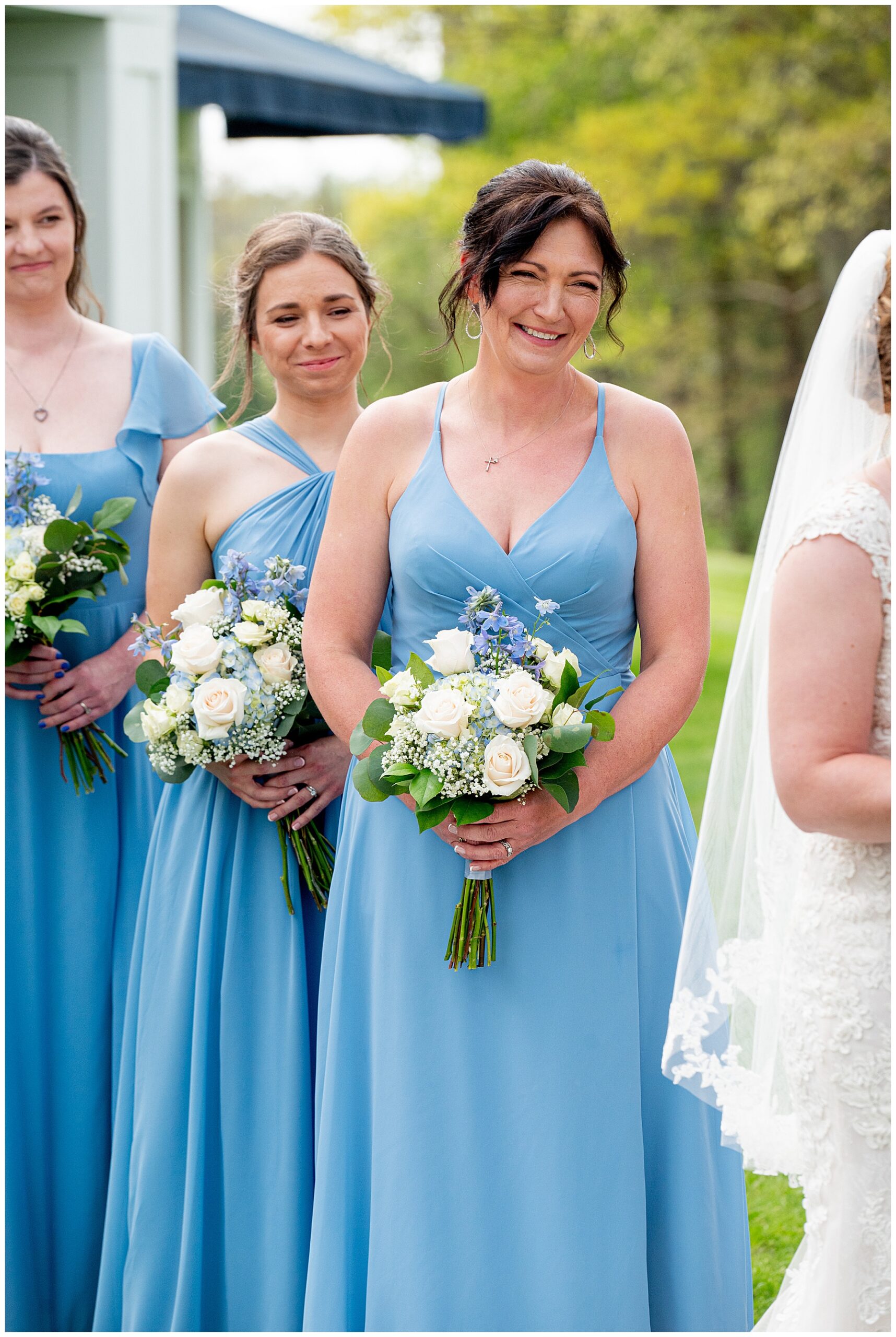 bridesmaids look on during the wedding ceremony smiling in light blue dresses 