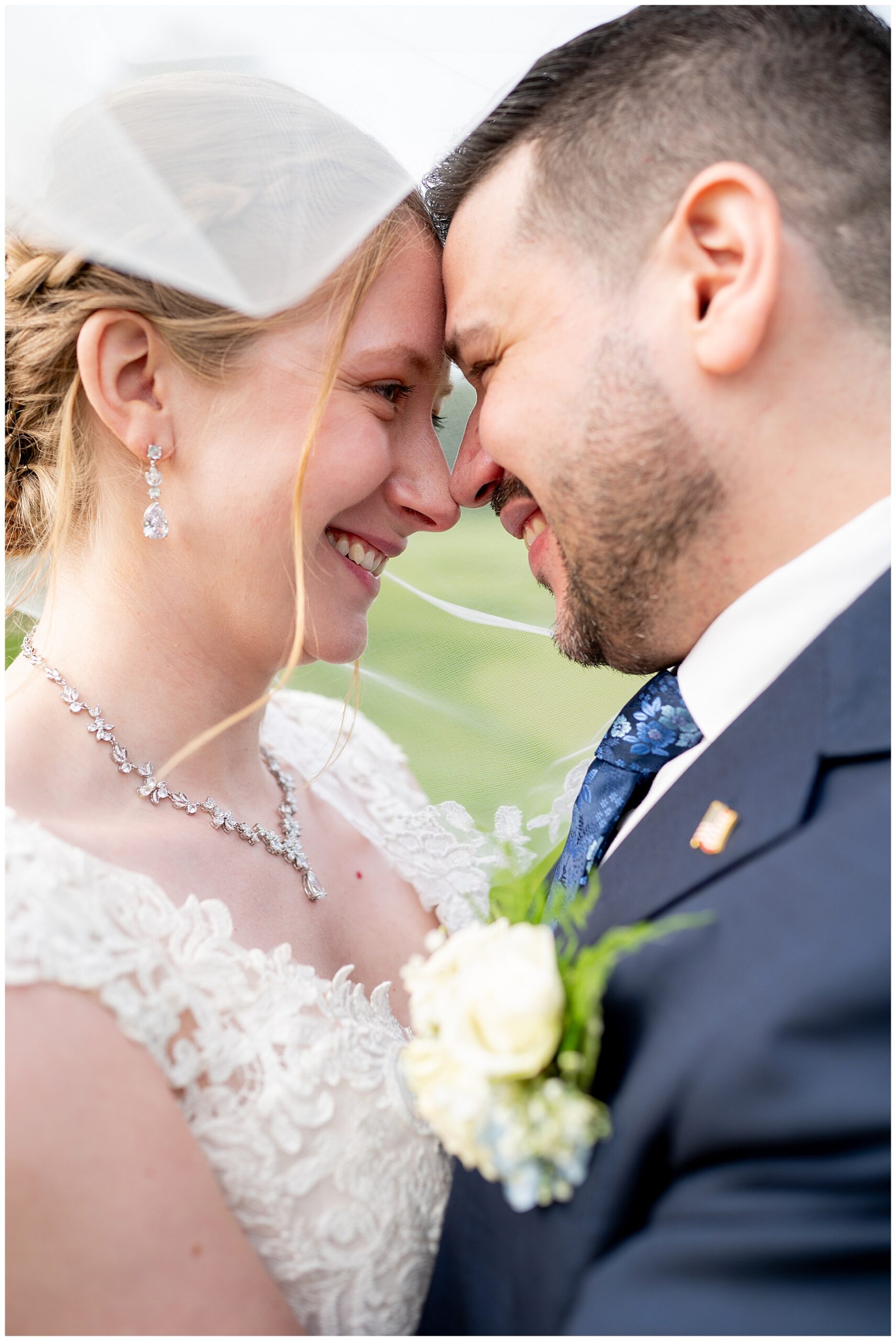 an up-close photo of the bride and groom smiling at each other underneath the bride's veil