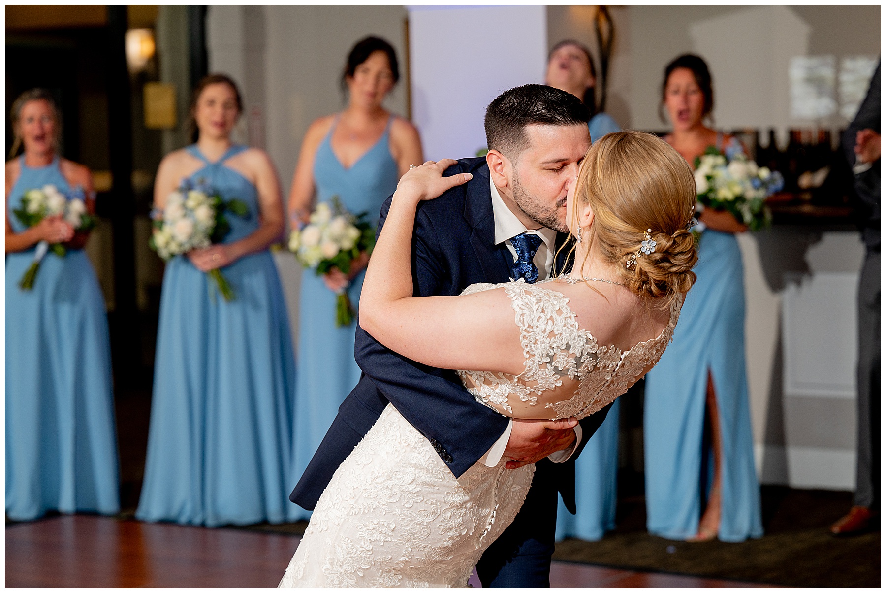 a photo of the bride & groom during their first dance as wedding party looks on 