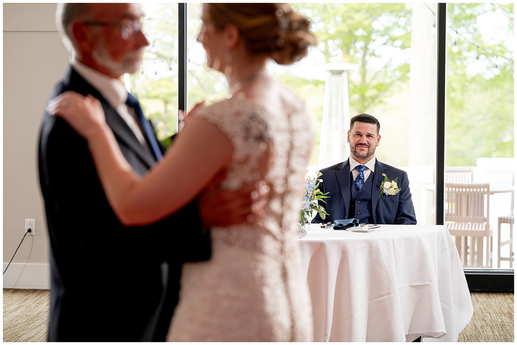 a photo of the groom smiling at the bride and her father dancing