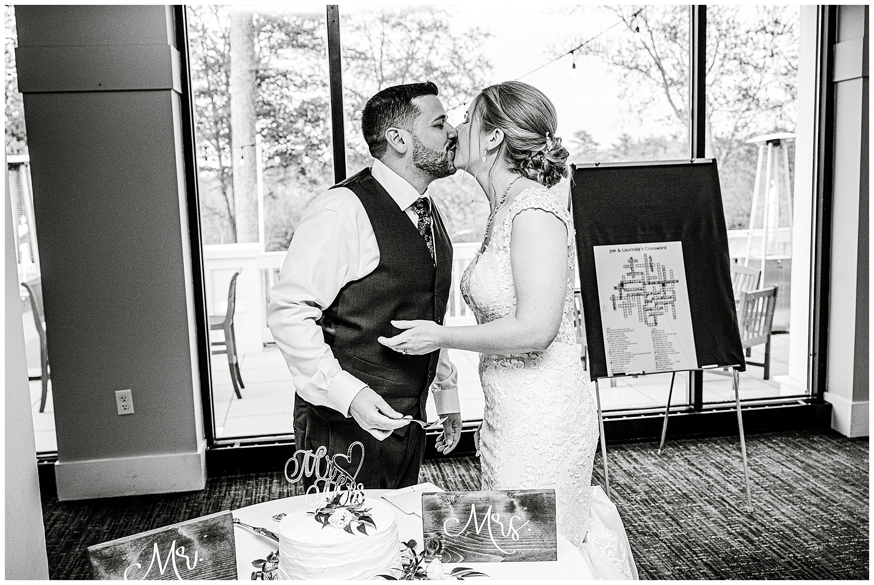 a black and white photo of the bride and groom kiss after cutting their wedding cake 