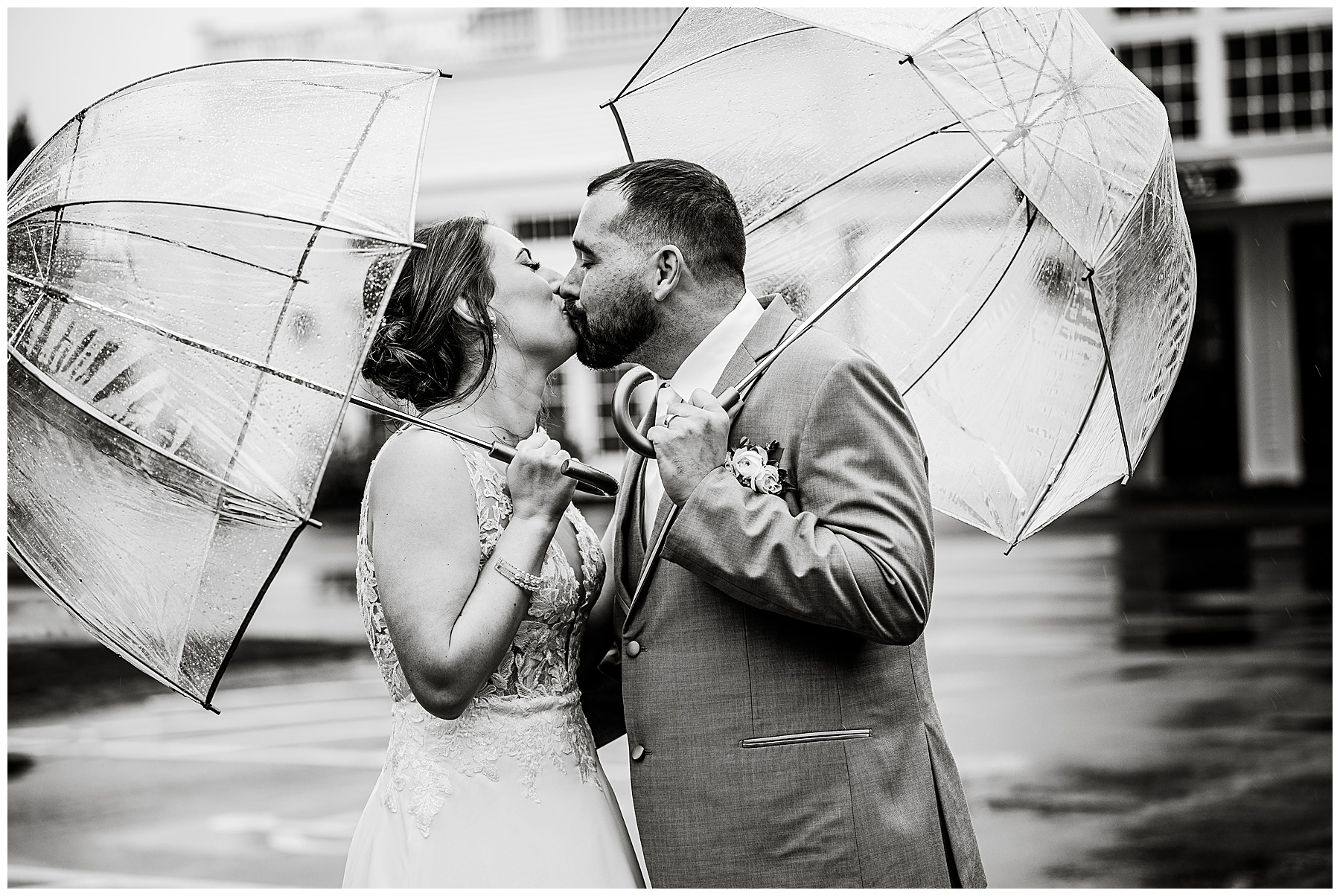 Bride and groom kissing under clear umbrellas at the Chocksett Inn on their rainy wedding day 