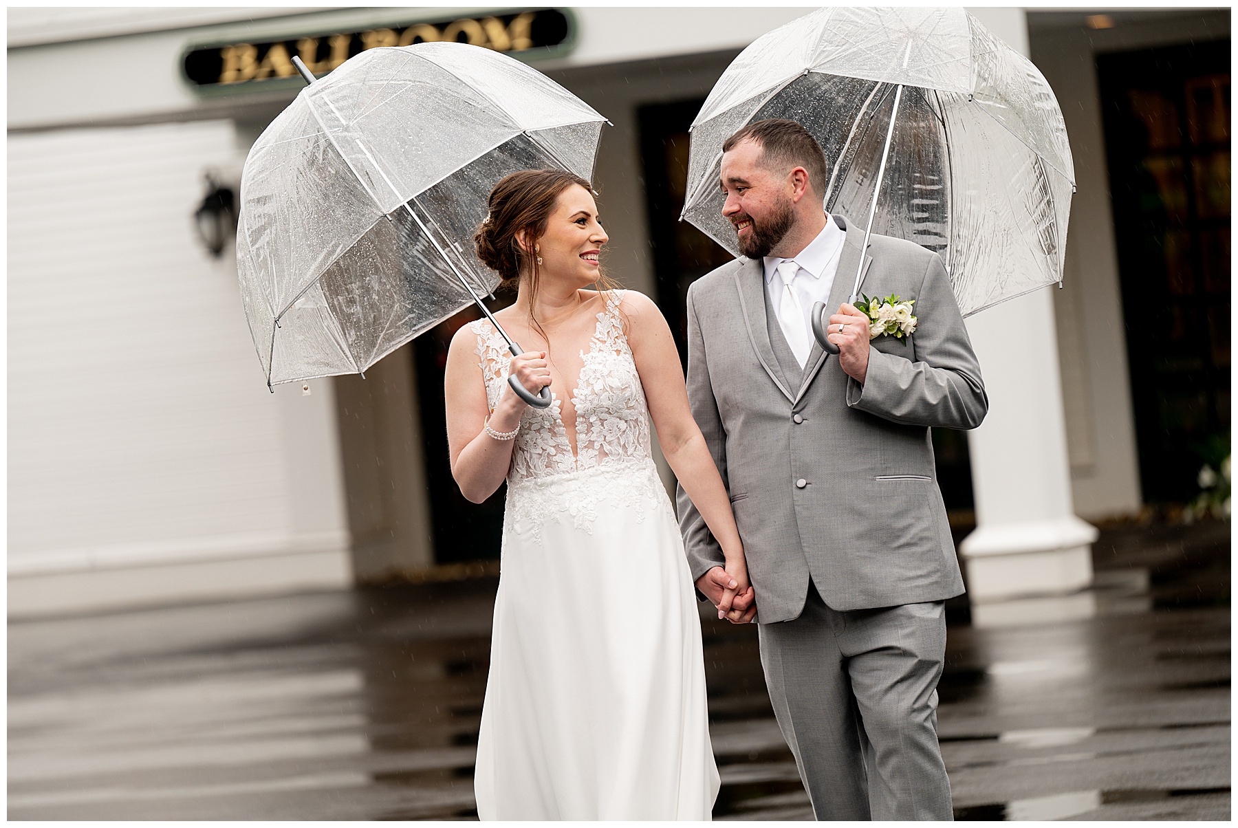 bride and groom walking outside in the rain holding clear umbrellas