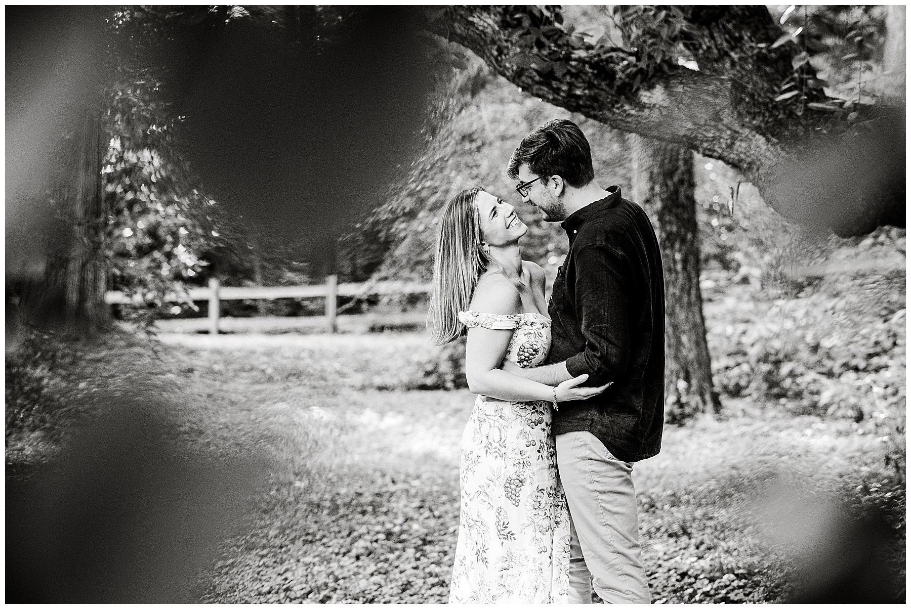 black and white photo of couple embracing surrounded by trees