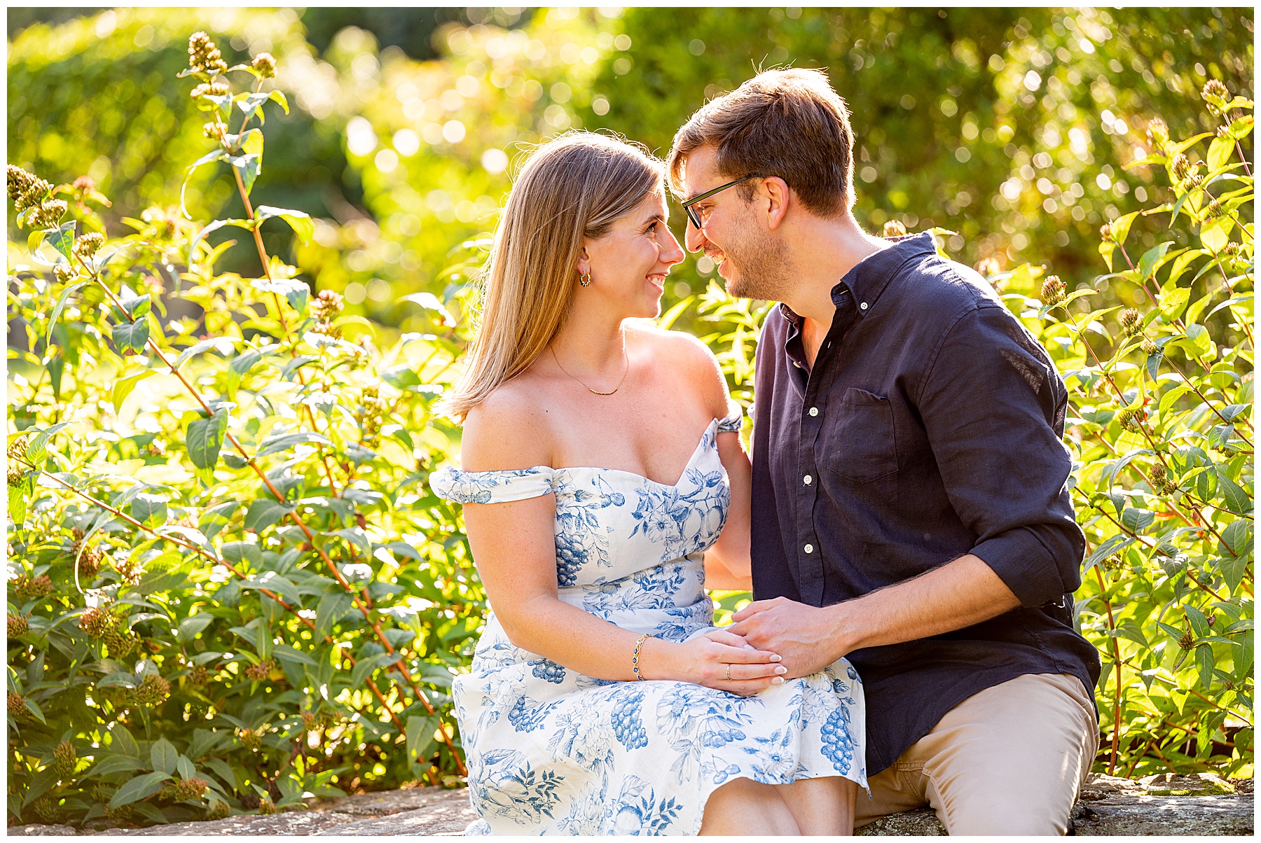 man and woman about to kiss during their Engagement Session surrounded by greenery and sunshine 