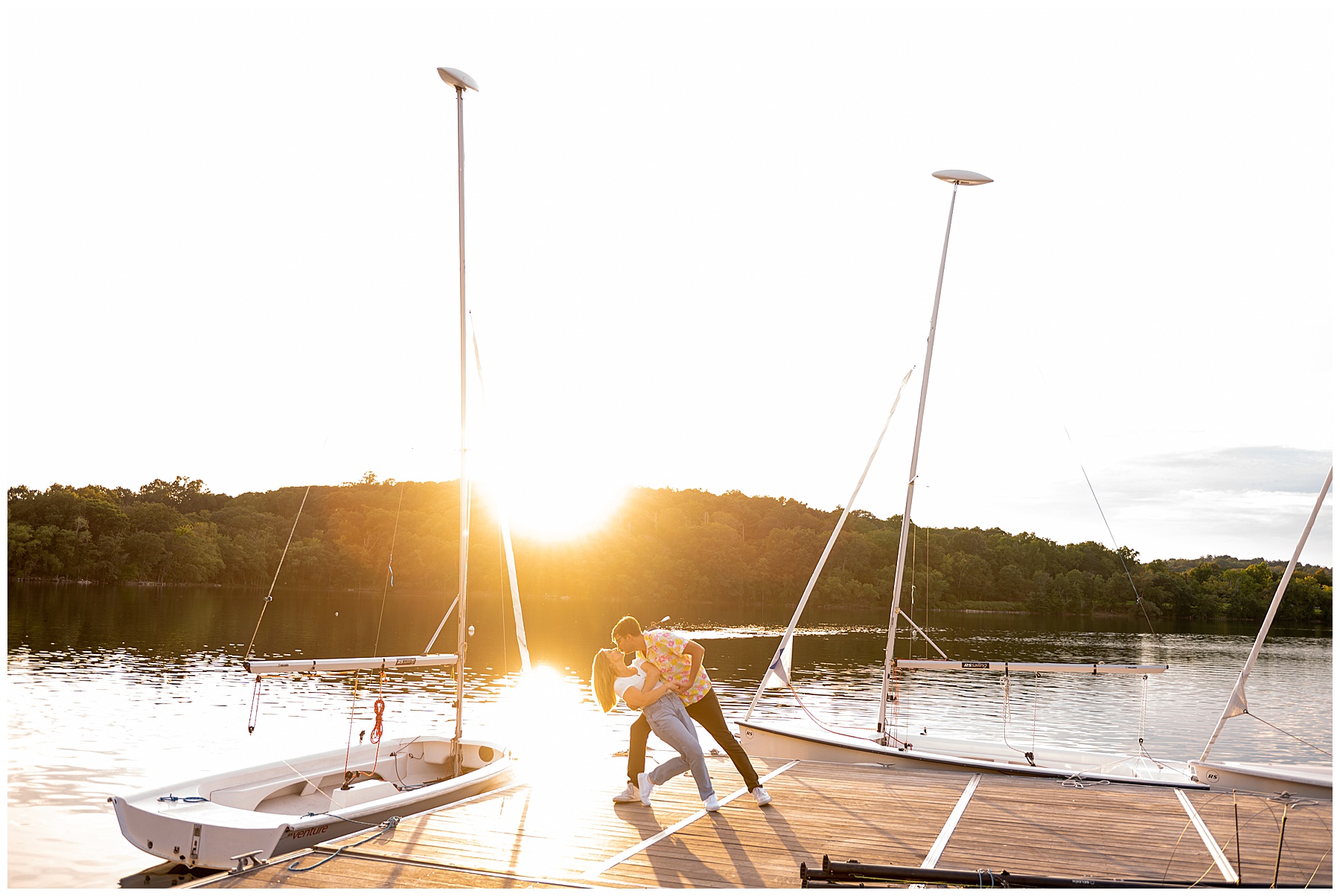 man dips the woman back as they kiss with the Jamaica Pond and sunset behind them