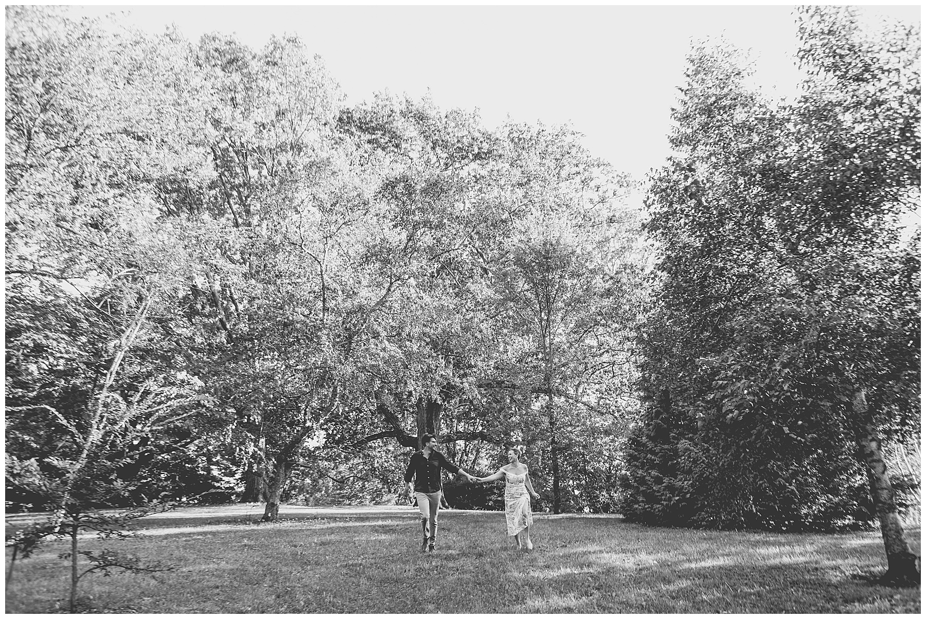 black and white photo of man and woman holding hands as they run across a field 