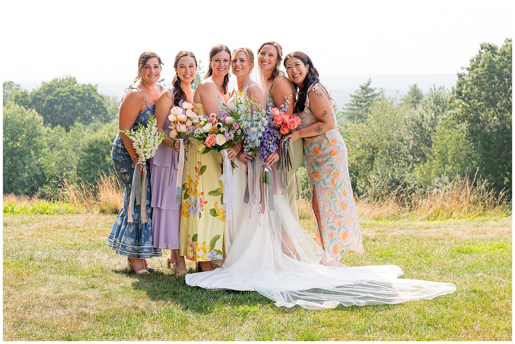 bride standing with her bridesmaids who are wearing bright floraled colored dresses and holding wildflower bouquets 