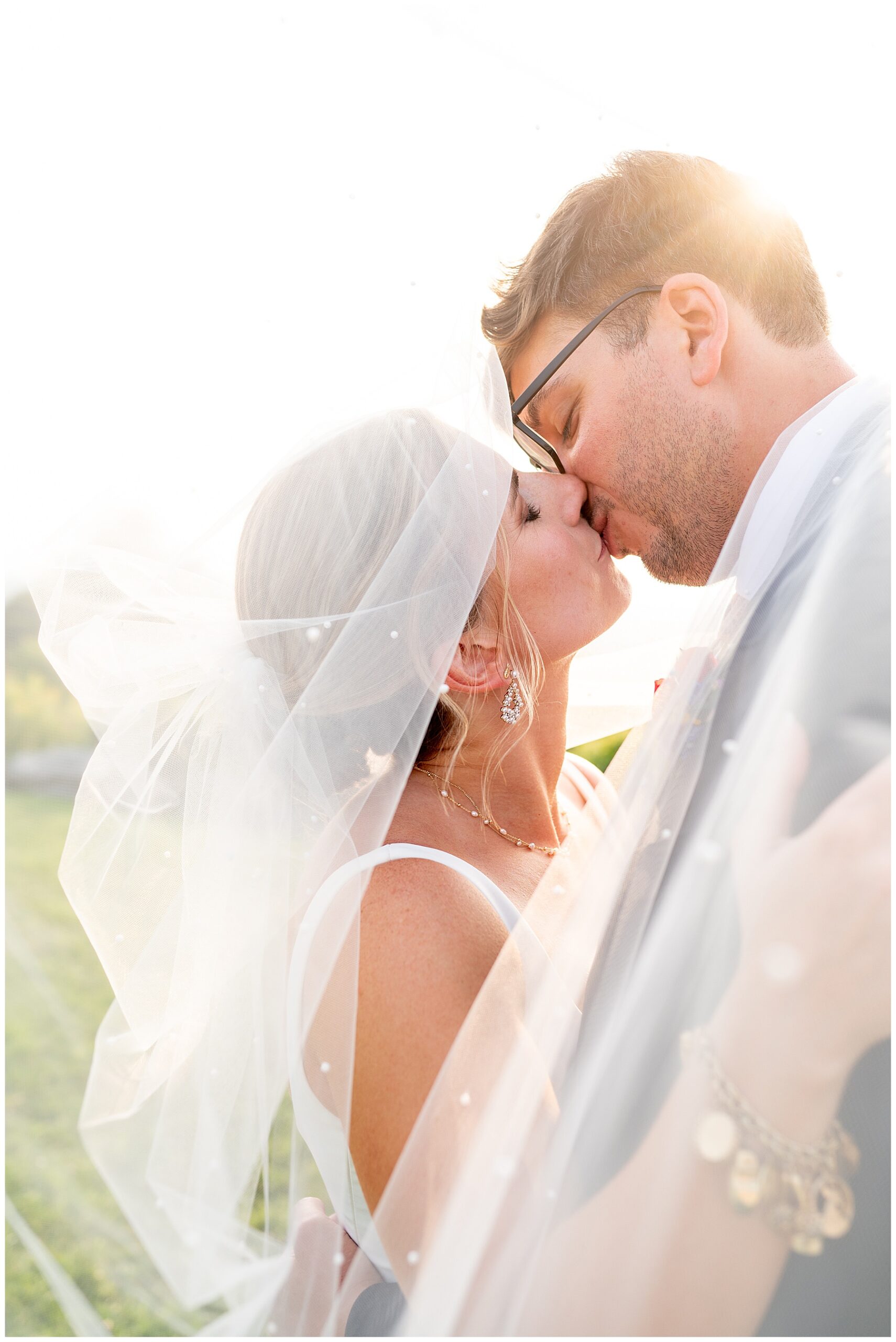 close up photo of bride and groom kissing underneath her veil 