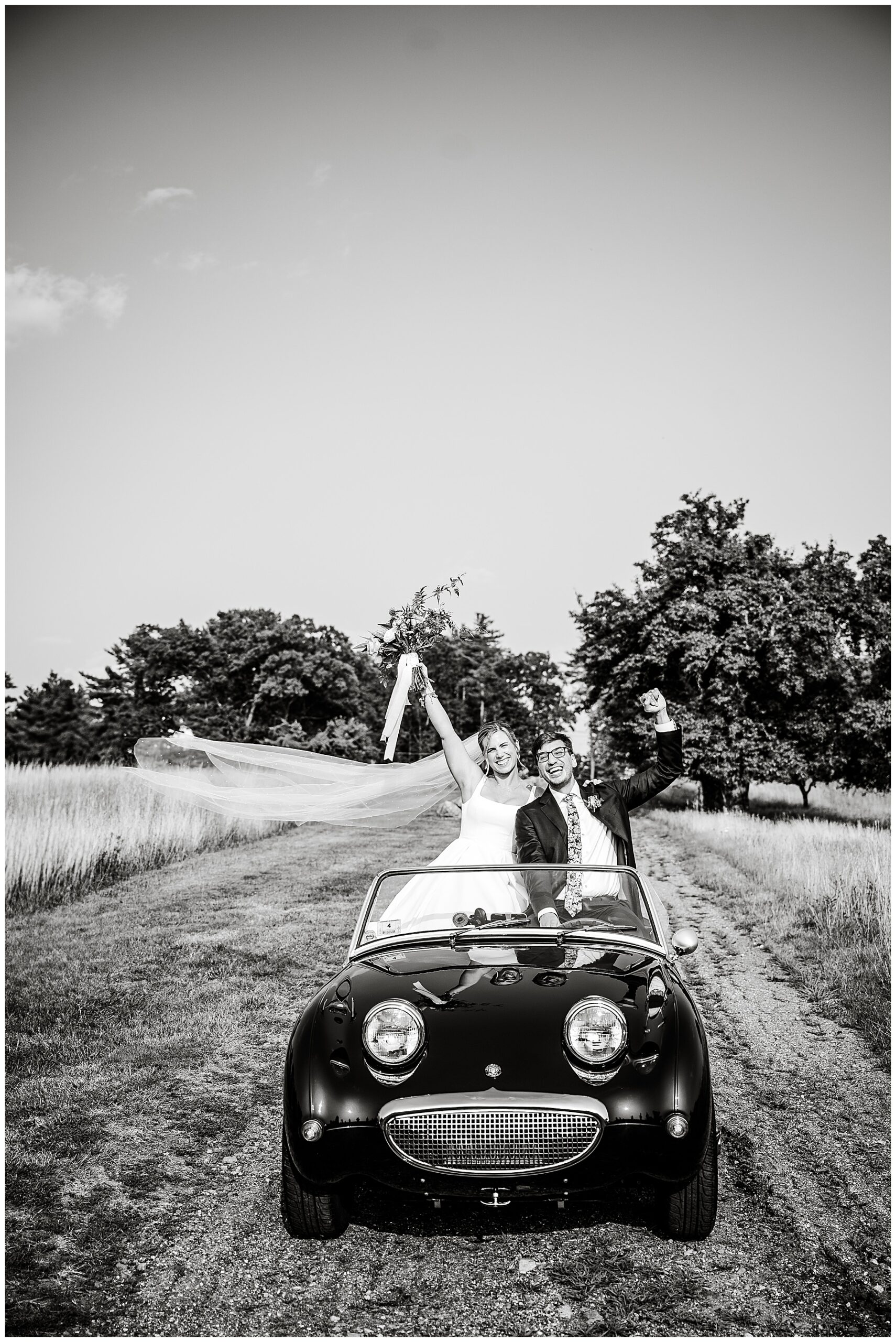 black and white photo of bride and groom sitting in vintage car 