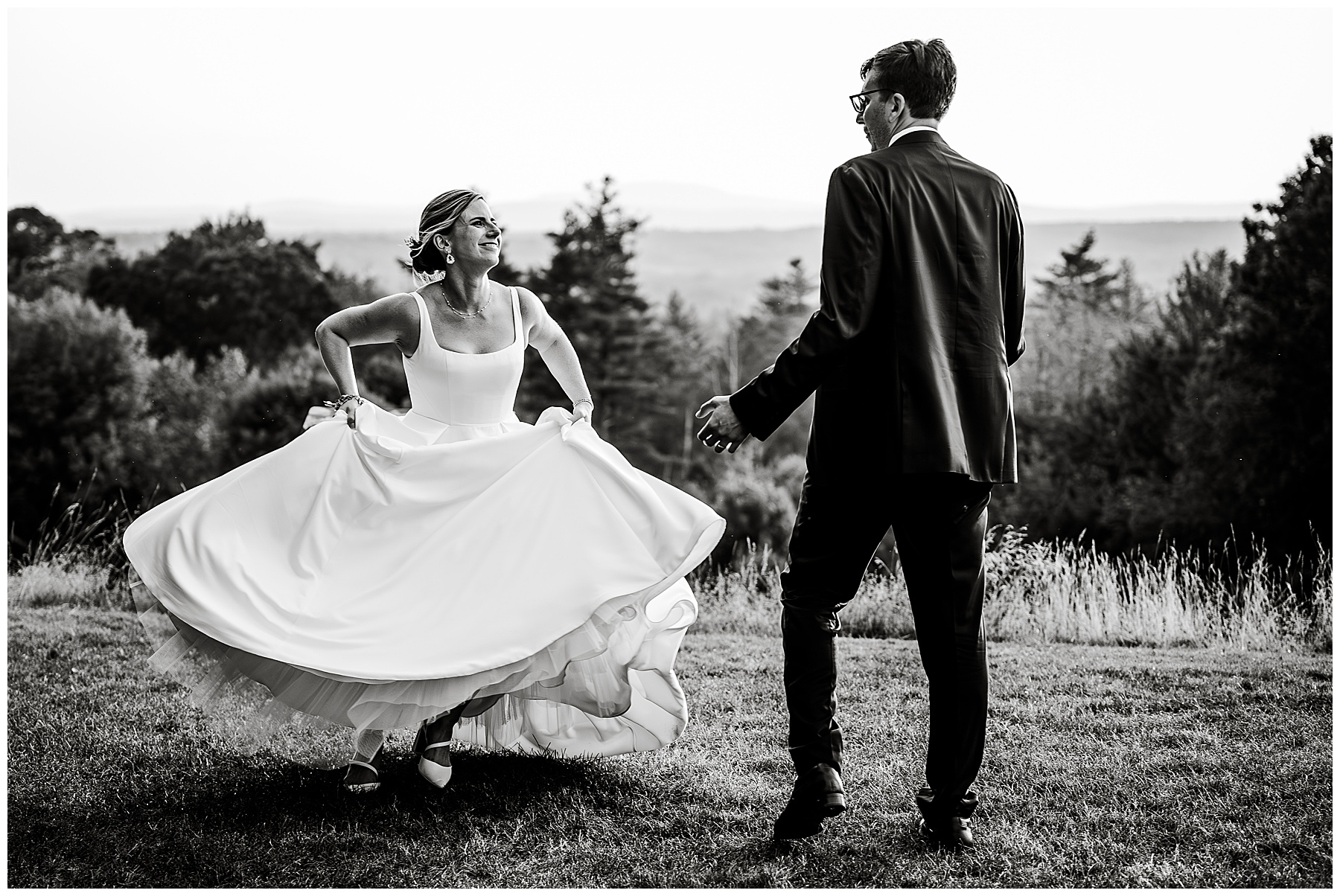 black and white photo of bride and groom dancing outside during sunset 