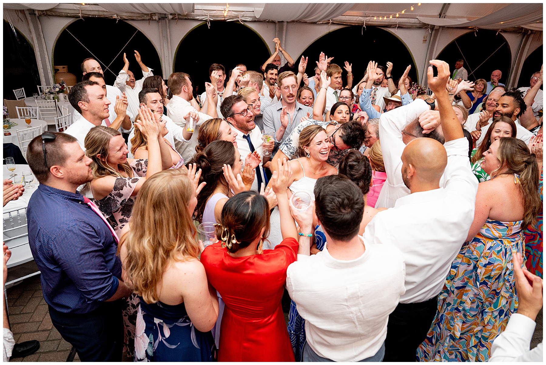 group photo of all the guests dancing around the bride and groom on the dance floor during the fruitlands museum wedding reception