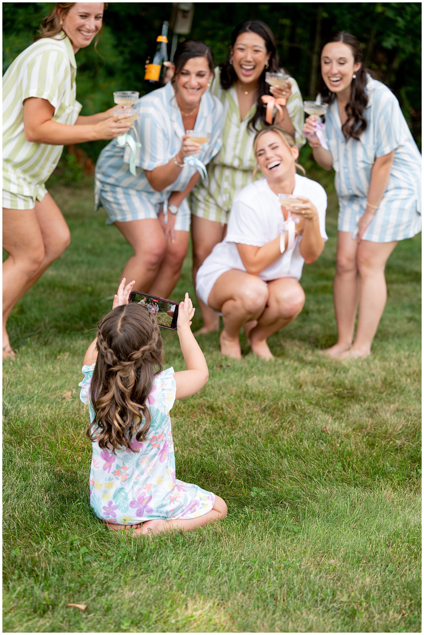 flower girl takes photo on iphone of bridesmaids and bride in their pajamas 