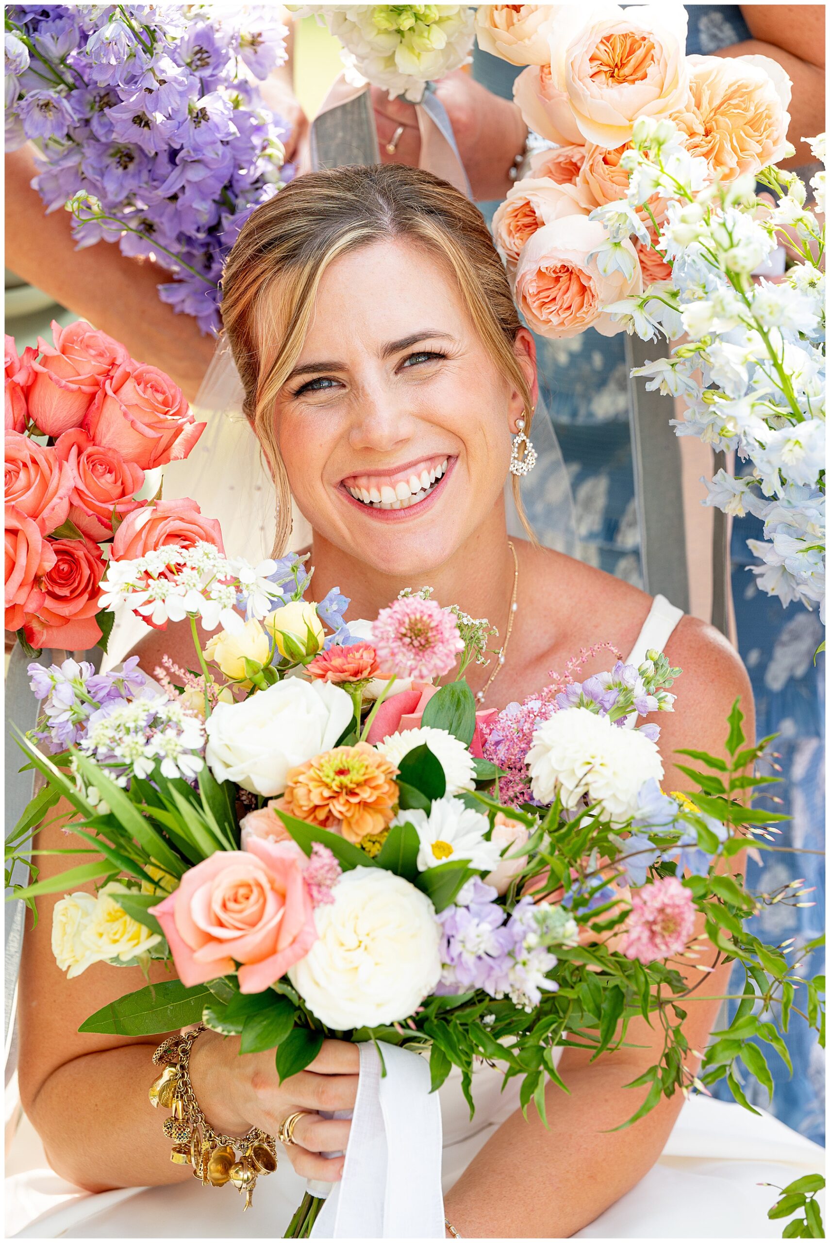 bride smiling as her head is surrounded by bouquets 