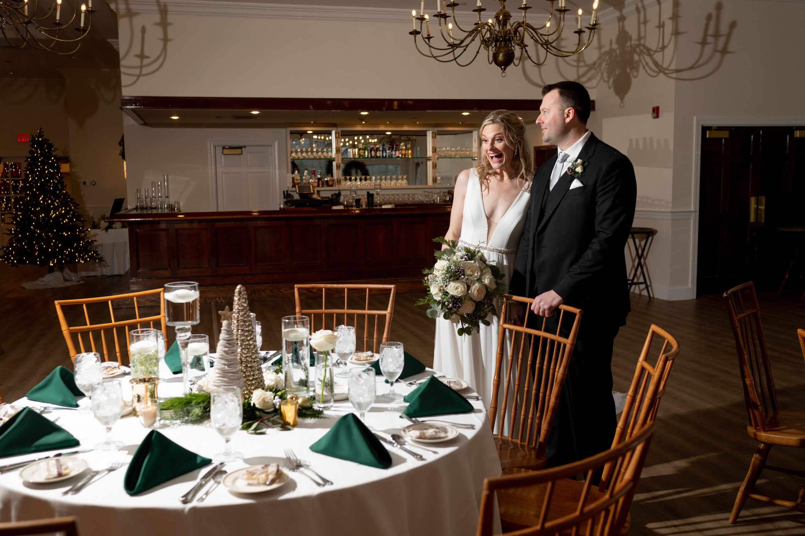 bride and groom smiling as they view their reception space decorated in christmas decor for their december wedding