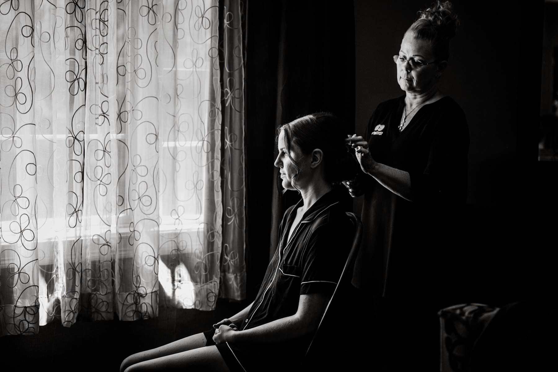 black and white photo of hair stylist finishing bride's hair