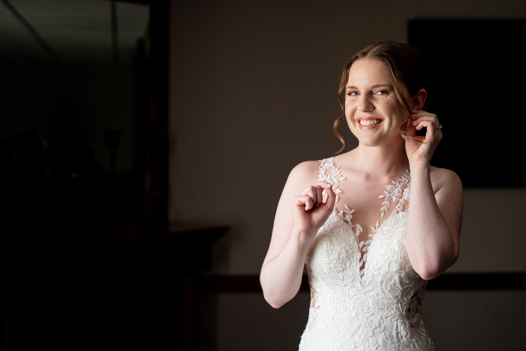 bride smiling at camera as she adjusts earring 