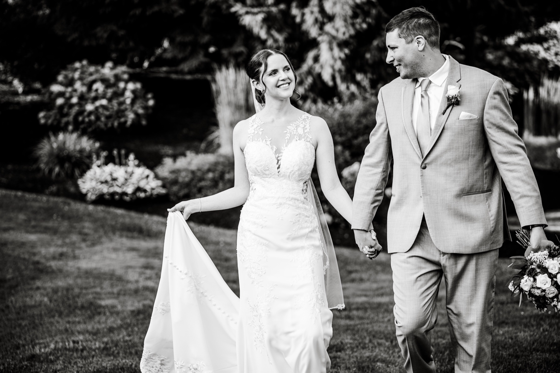 white and black photo of bride and groom smiling and holding hands 