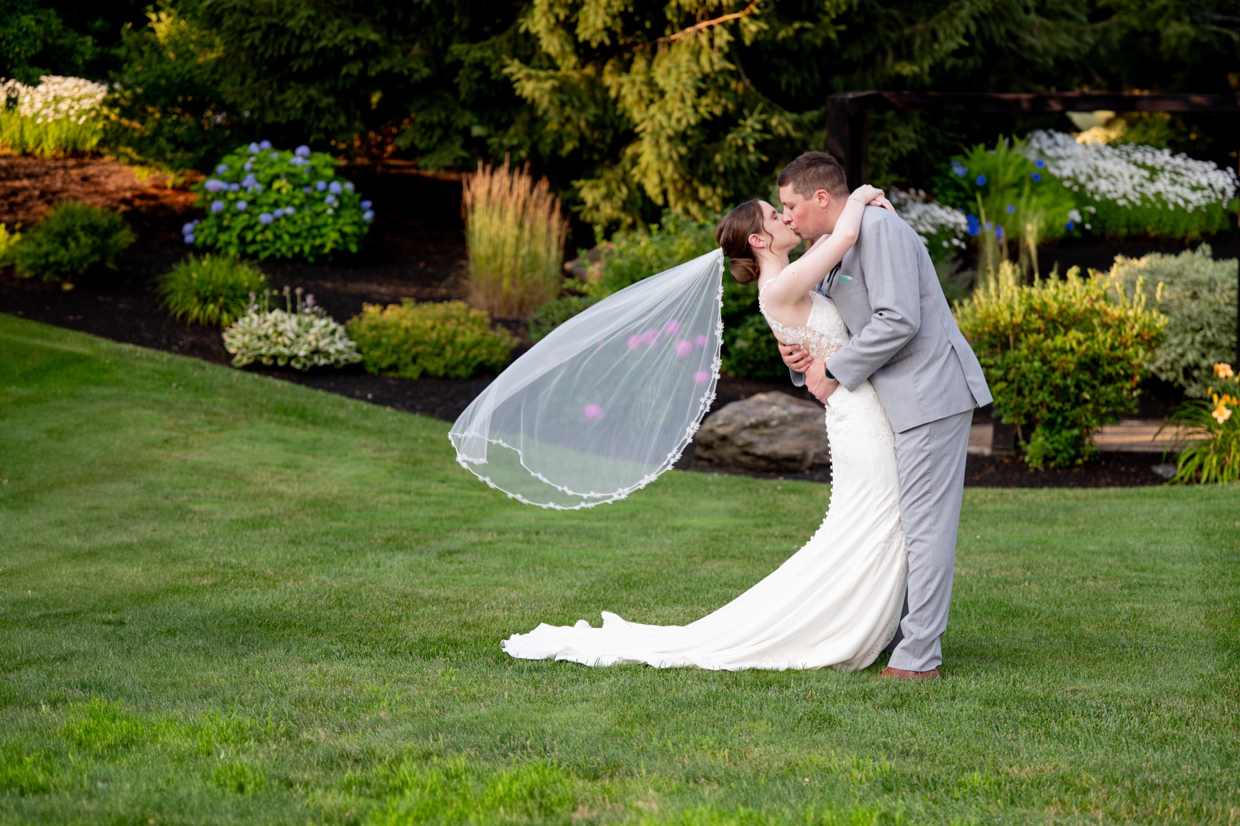 bride and groom kissing as the wedding veil blows in the wind