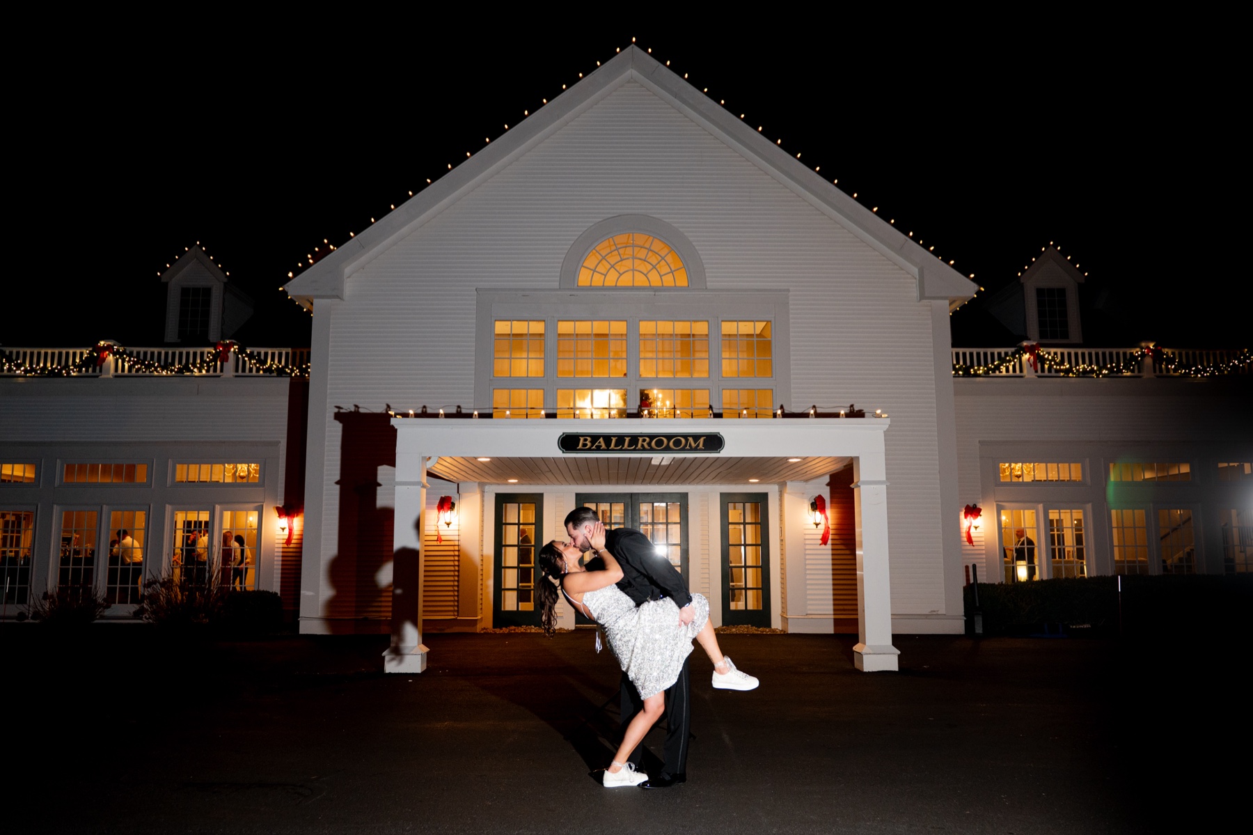 bride and groom kissing in front of wedding reception venue in the evening