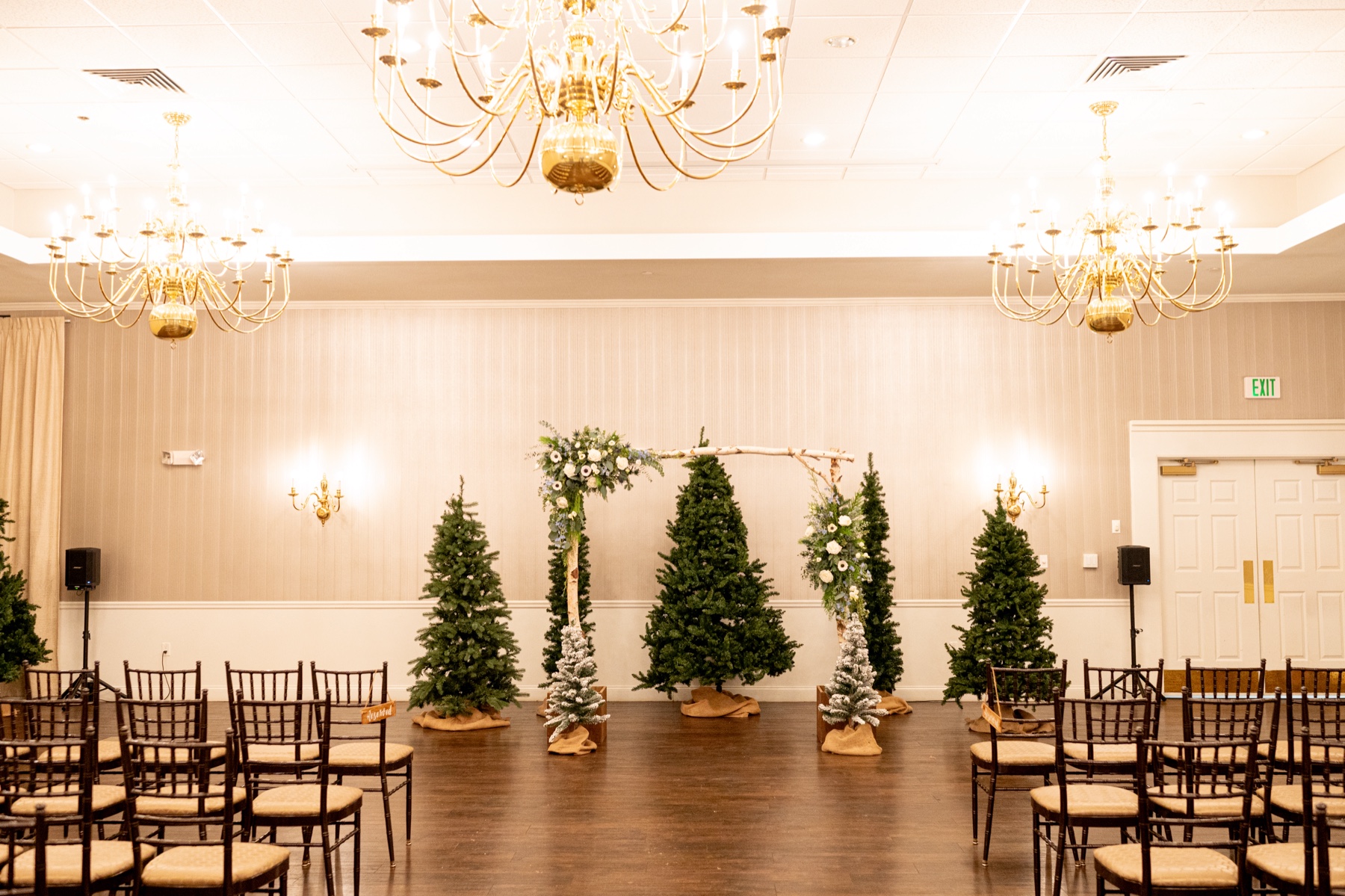 a Winter Wonderland Wedding ceremony styled with christmas trees and an altar decorated with greenery and pine cones 