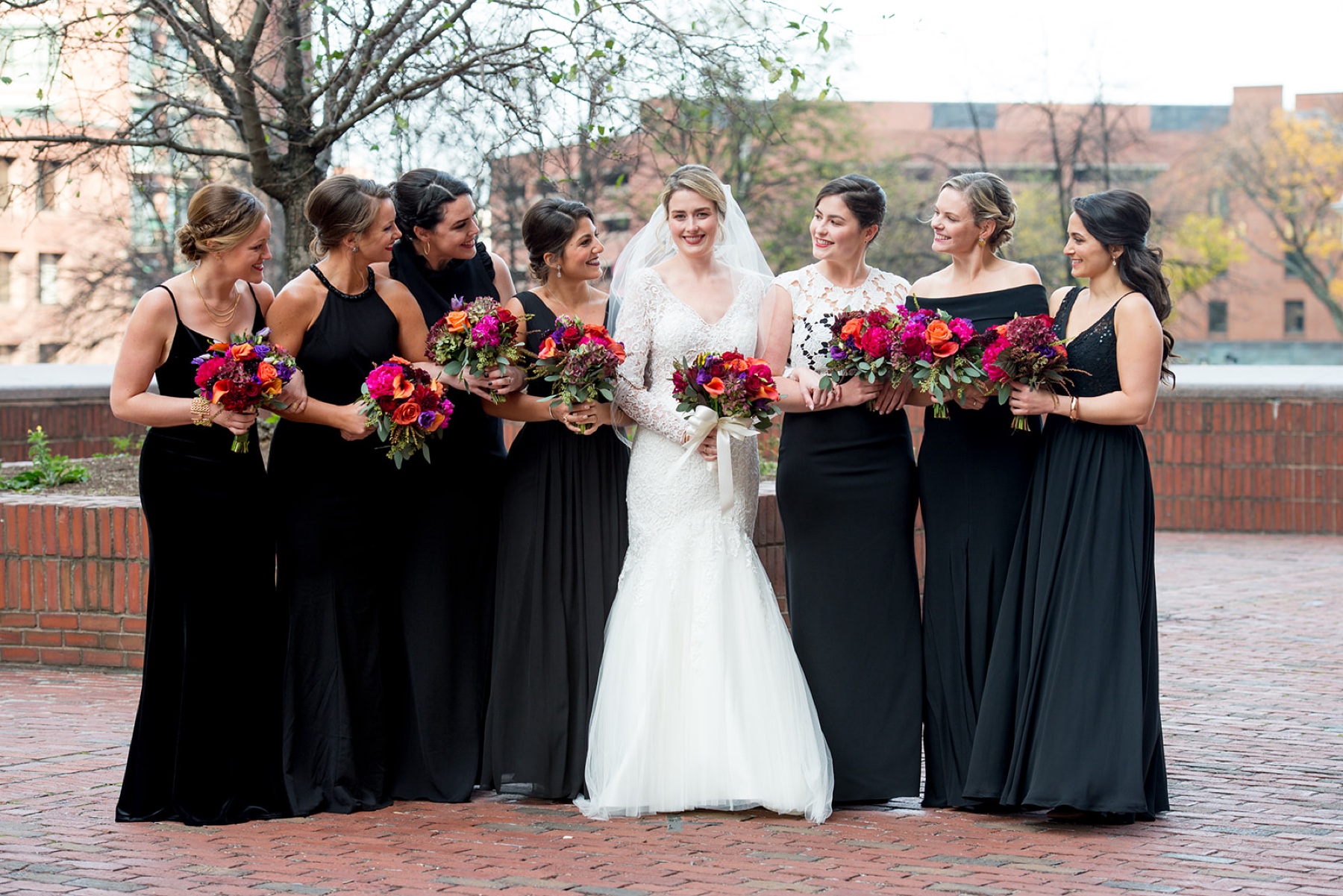 a Winter Wonderland Wedding party wearing black dresses and holding pink and red bridal bouquets 