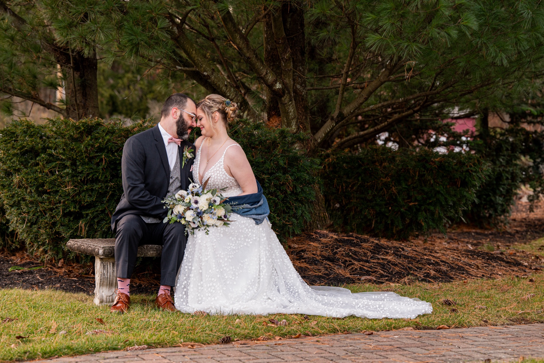 bride and groom sitting on a bench together before their Winter Wonderland Wedding ceremony 