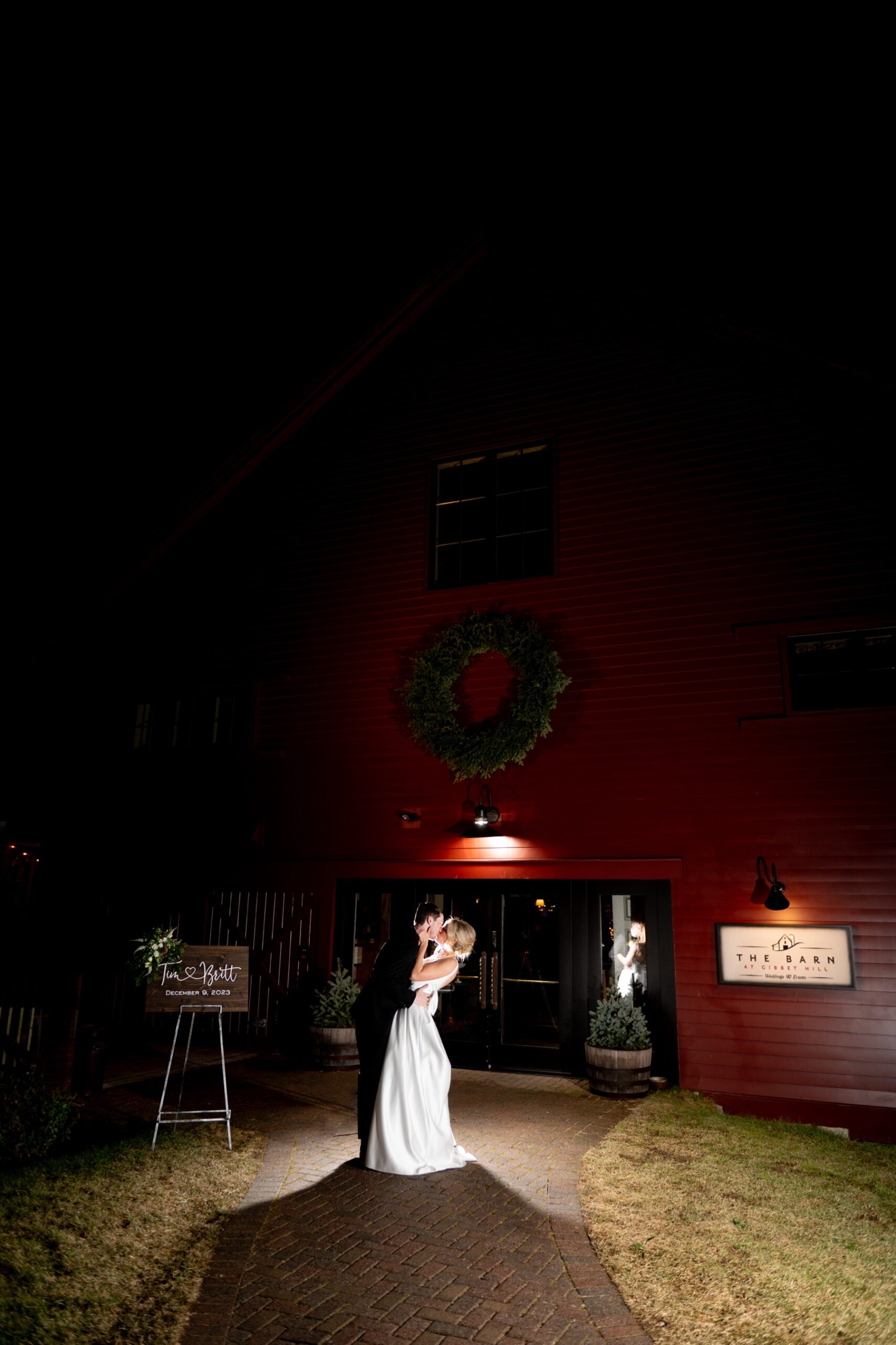 bride and groom kissing outside a barn at night on their wedding day 