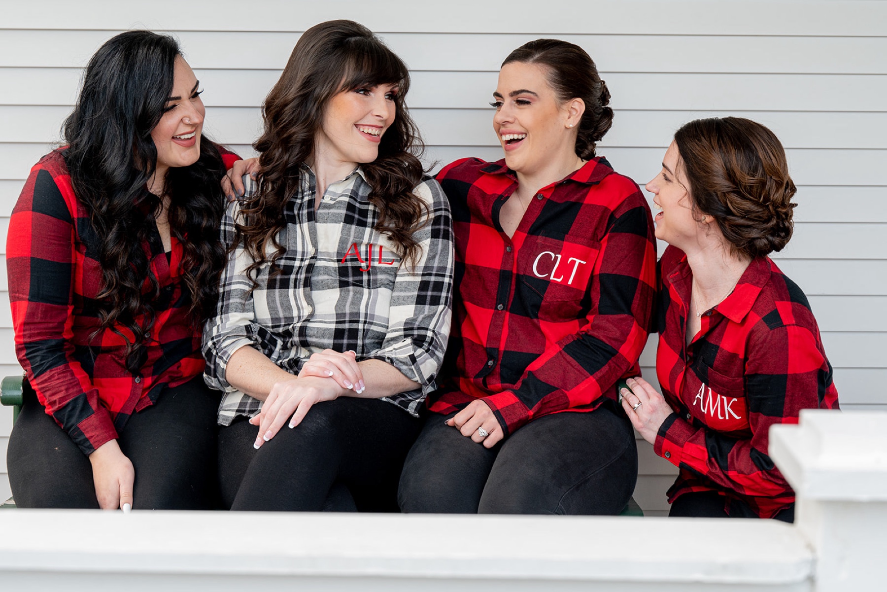 bride and bridesmaids sitting on a bench wearing red and black checkered flannel pjs 