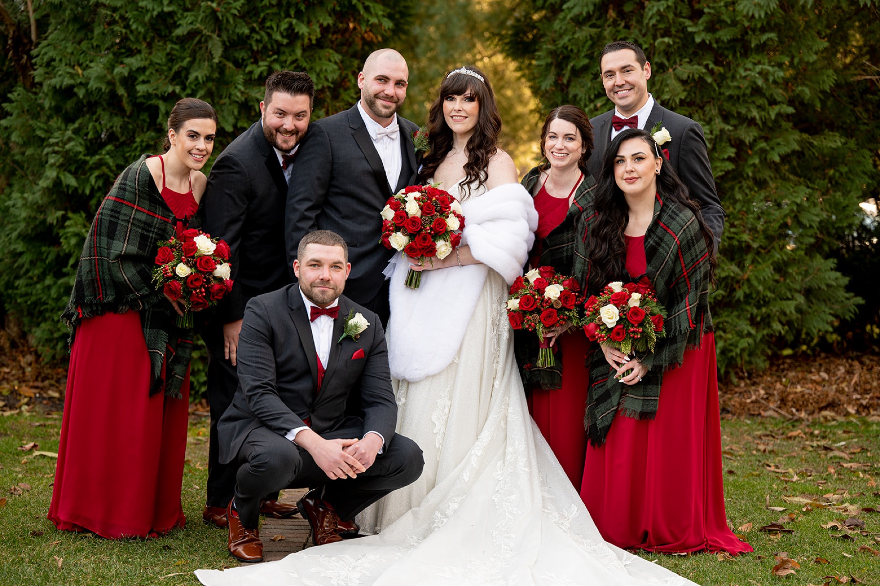 wedding party with red dresses and bowties and red and green shawls for the bridesmaids to keep warm