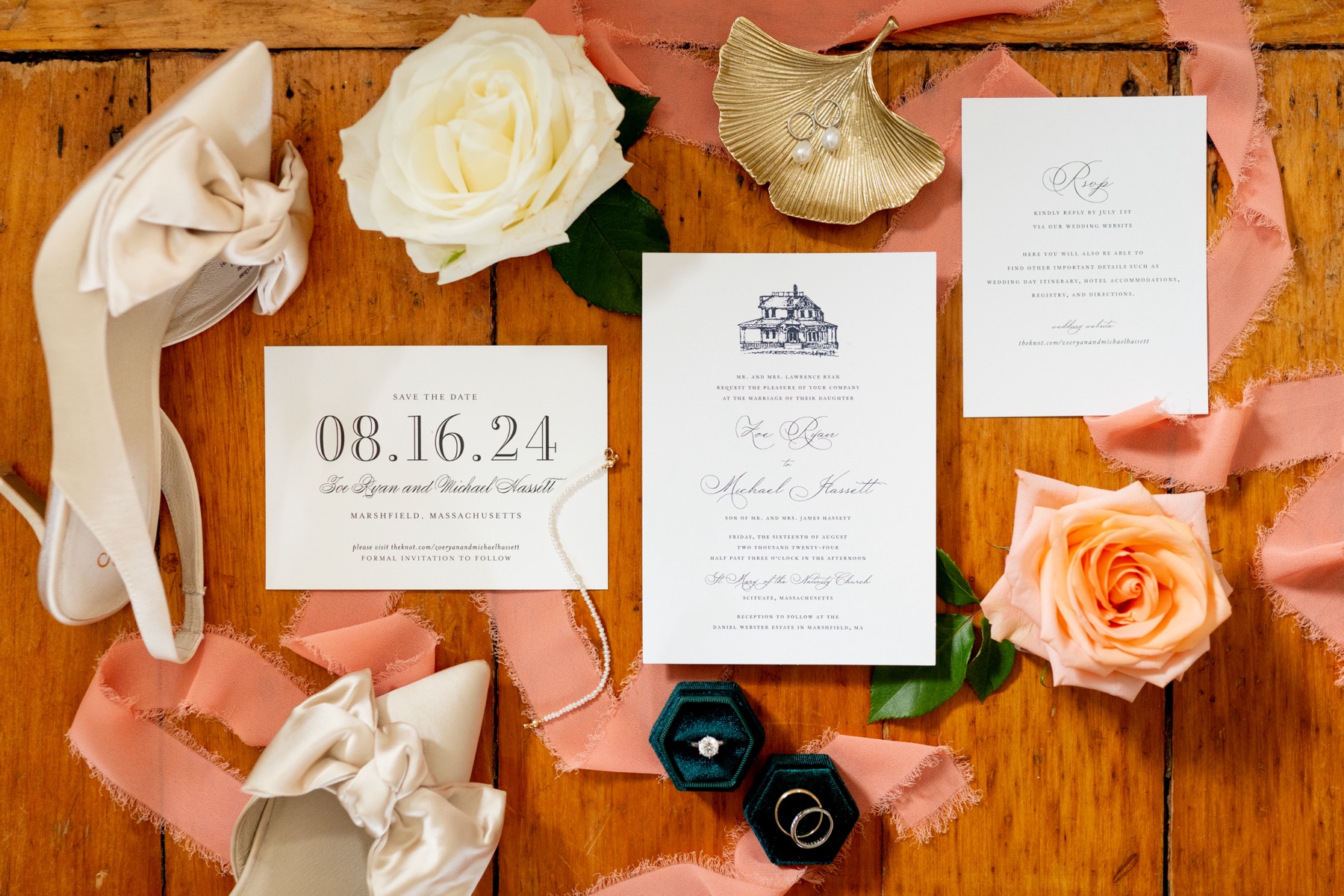 white wedding invitations and bridal shoes with white flowers and pink ribbon laying on a hardwood floor