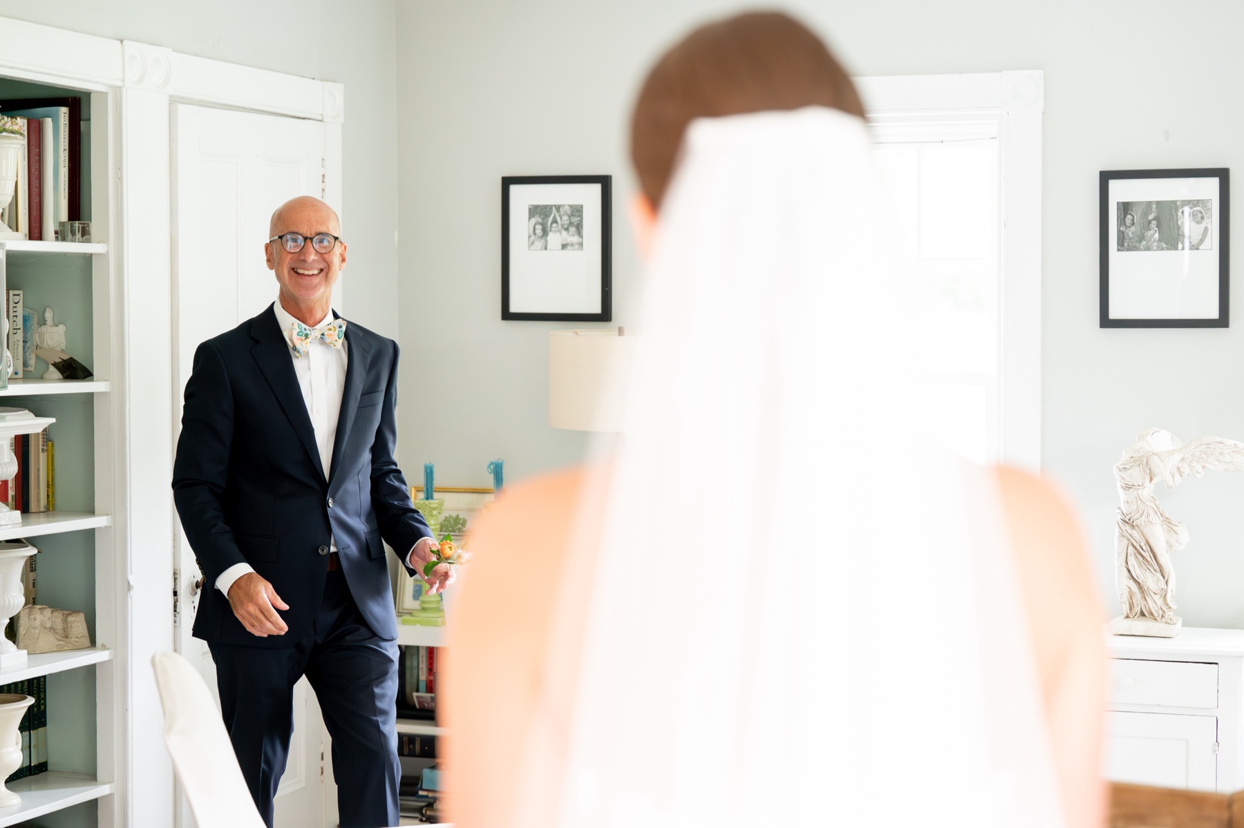 father of the bride walking into the room for the first look with his daughter smiling 