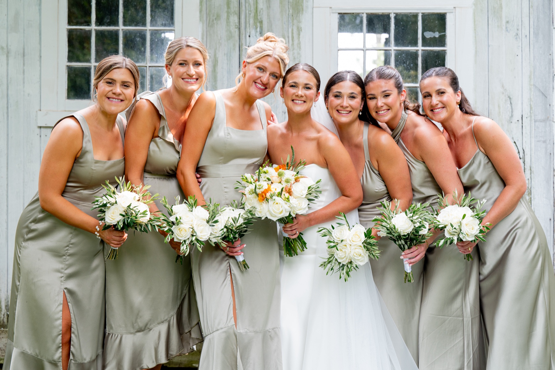 bride and her bridesmaids wearing light green satan dresses with white and green floral bouquets 